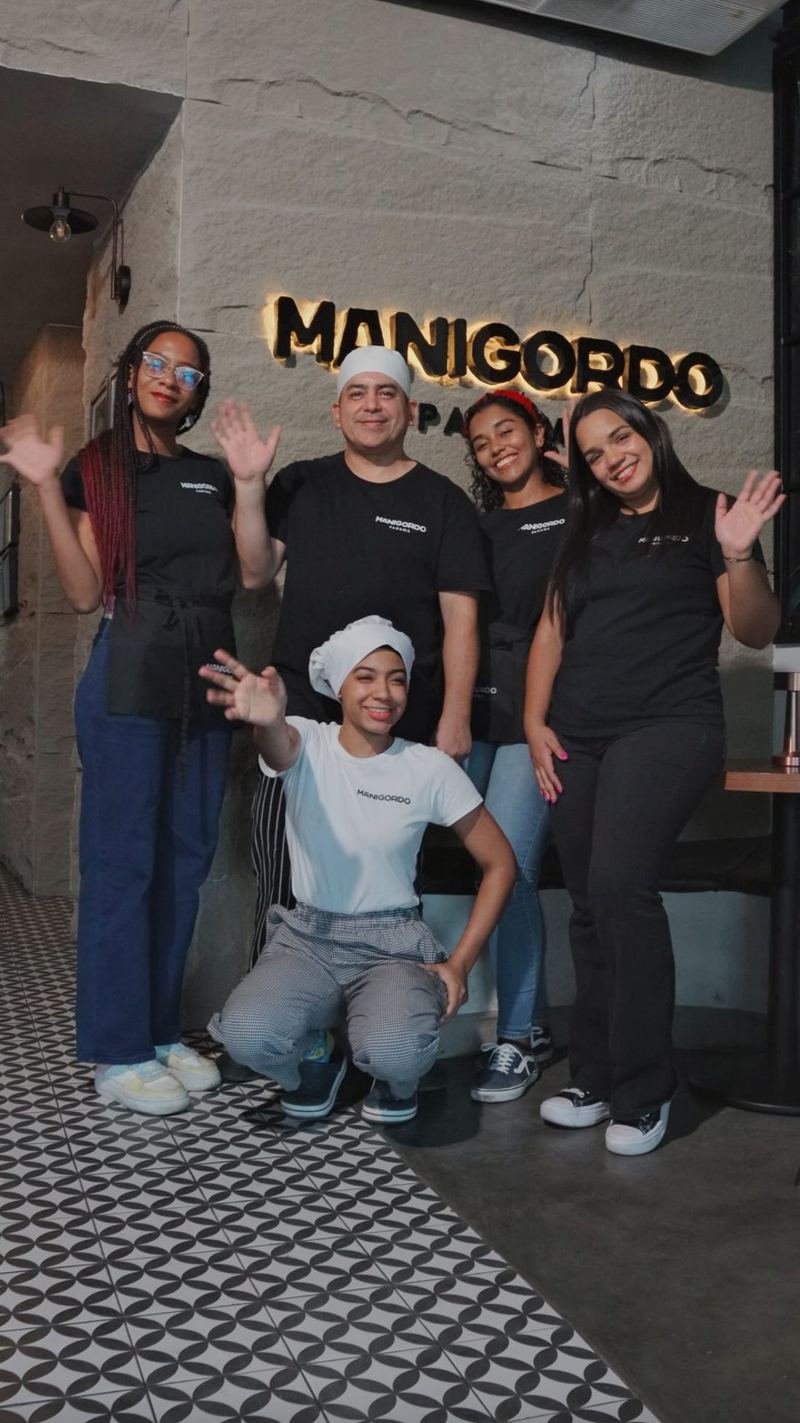 El equipo de cocina y barra saludando frente al letrero de Manigordo